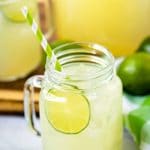 Limemade in a glass jar with a lime and paper straw.