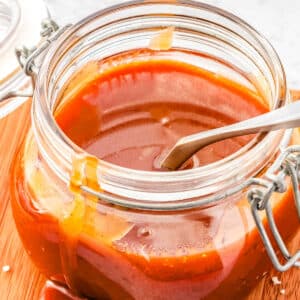 The finished salted caramel recipe in a glass jar with a spoon in it.