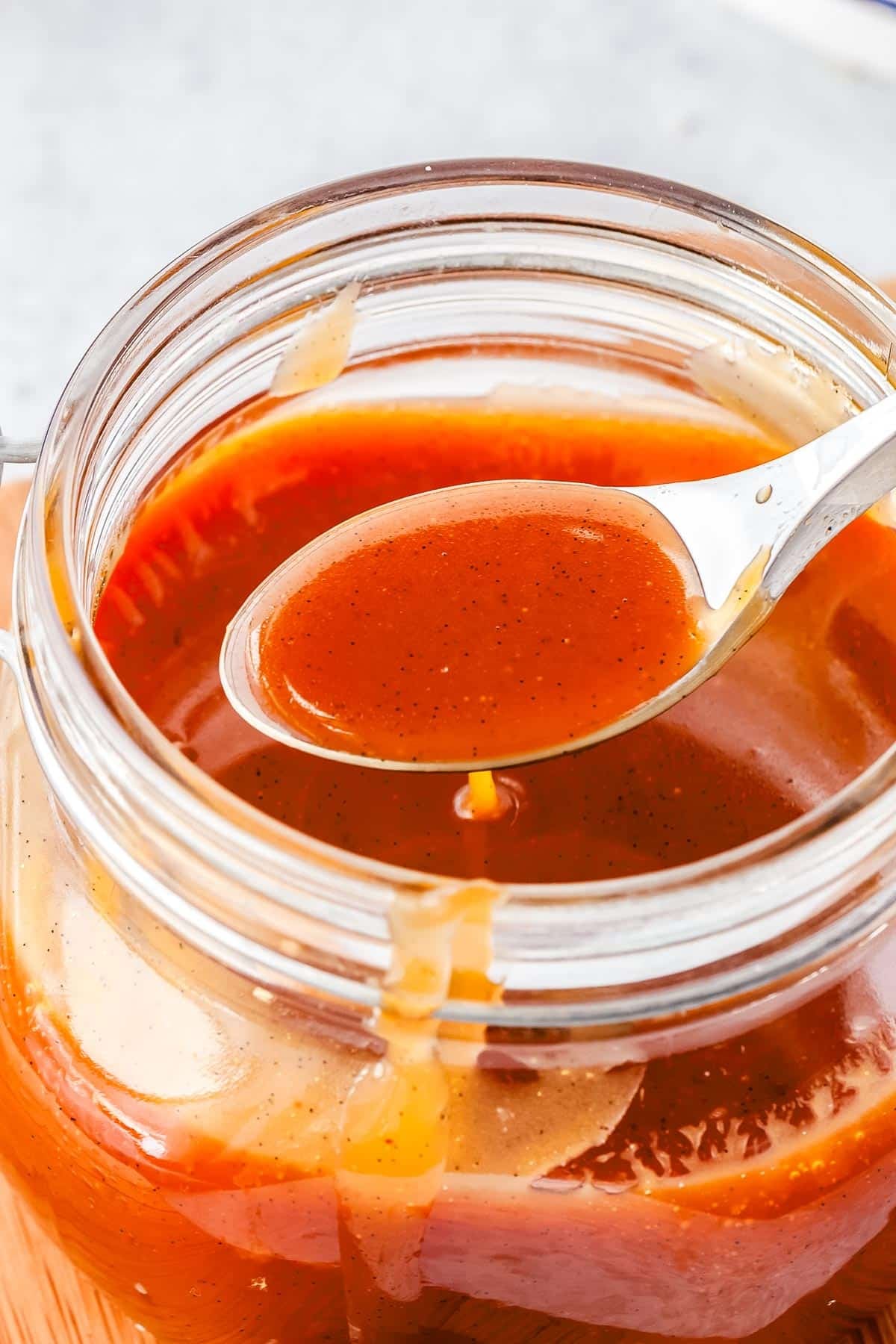 A spoon lifting some salted caramel from a jar.