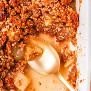 A serving spoon in a baking dish of crisp.