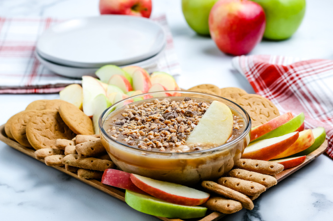 The cream cheese caramel apple dip on a serving platter with apple slices and graham cracker sticks.