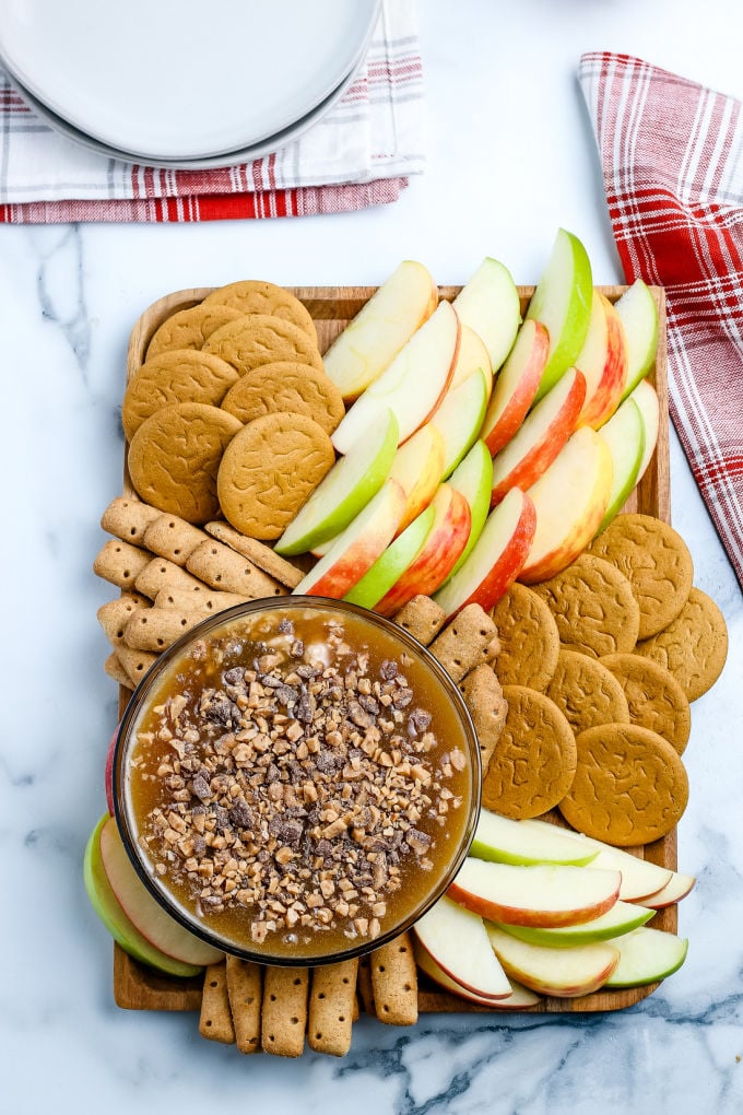 An over head picture of caramel apple dip on a serving platter with apple slices and graham crackers.