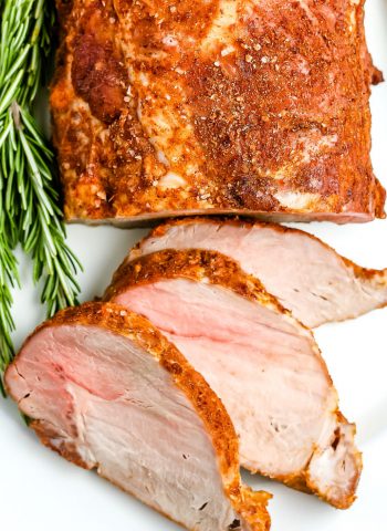A close up picture of the finished roasted pork loin on a white serving platter.