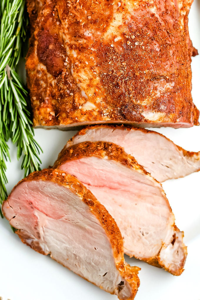 A close up picture of the finished roasted pork loin on a white serving platter.
