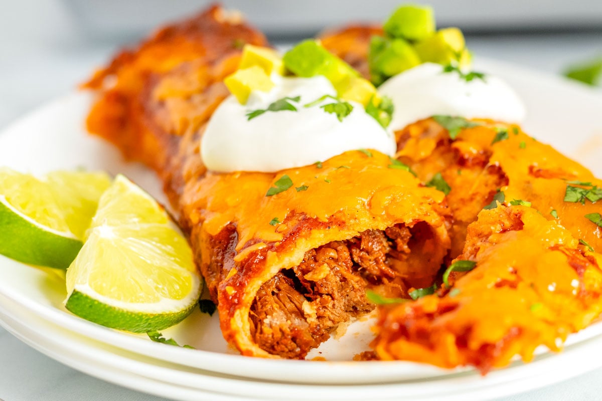 An enchilada on a white plate that's been cut into so you can see the inside.