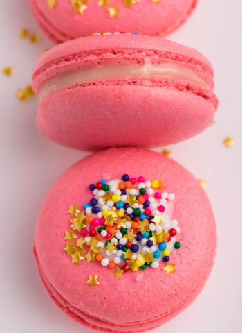 A close up picture of pink macarons on a white plate.