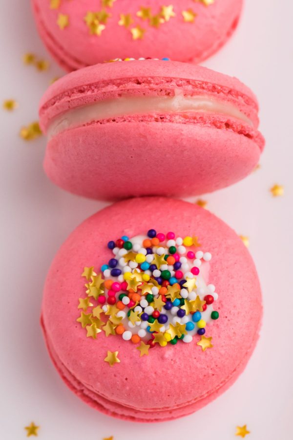 A close up picture of pink macarons on a white plate. 