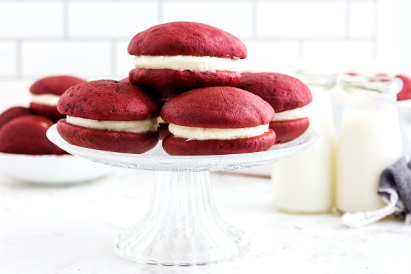 Five red velvet whoopie pies on a cake stand. 