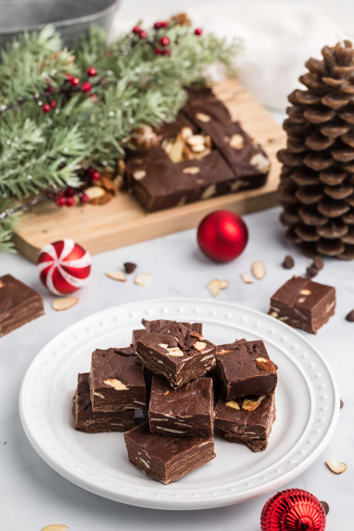 Chocolate Chip Fudge on a white platter with Christmas decorations around the platter. 