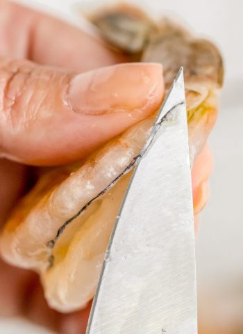 A knife taking out the vein of a shrimp.