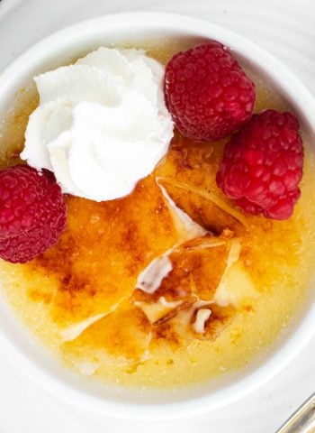 A close up picture of creme brulee with its crackly topping cracked into.