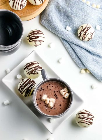 An overhead picture of Hot Chocolate Bombs whole and mixed together in a mug of warm milk to make hot cocoa.