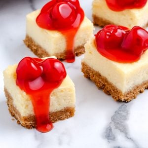 A close up picture of sliced Cheesecake Bars with cherry filling on top.