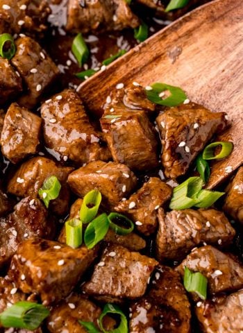 An overhead, close up picture of the finished Teriyaki Steak Tips garnished with sesame seeds and green onions.