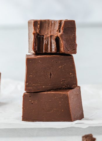 Three pieces of fudge stacked on top of each other, and the top piece has a bite taken out of it.
