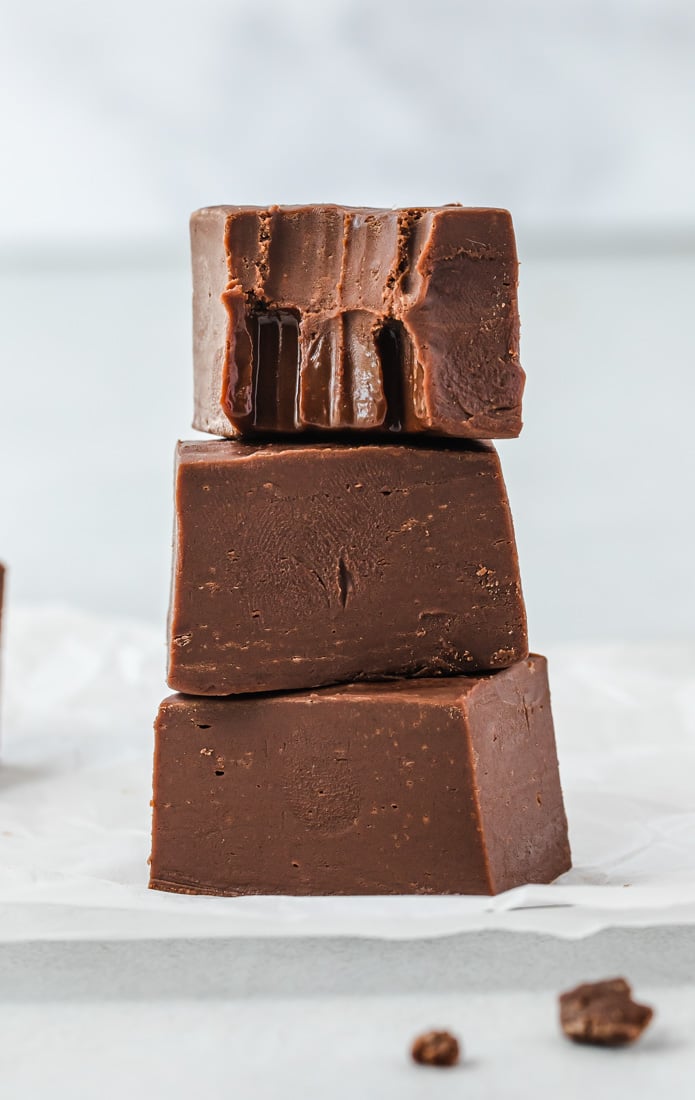 Three pieces of fudge stacked on top of each other, and the top piece has a bite taken out of it. 