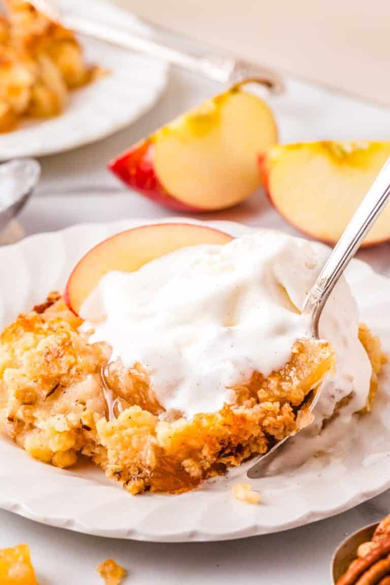 Apple dump cake with pie filling scooped onto a white plate and topped with ice cream.