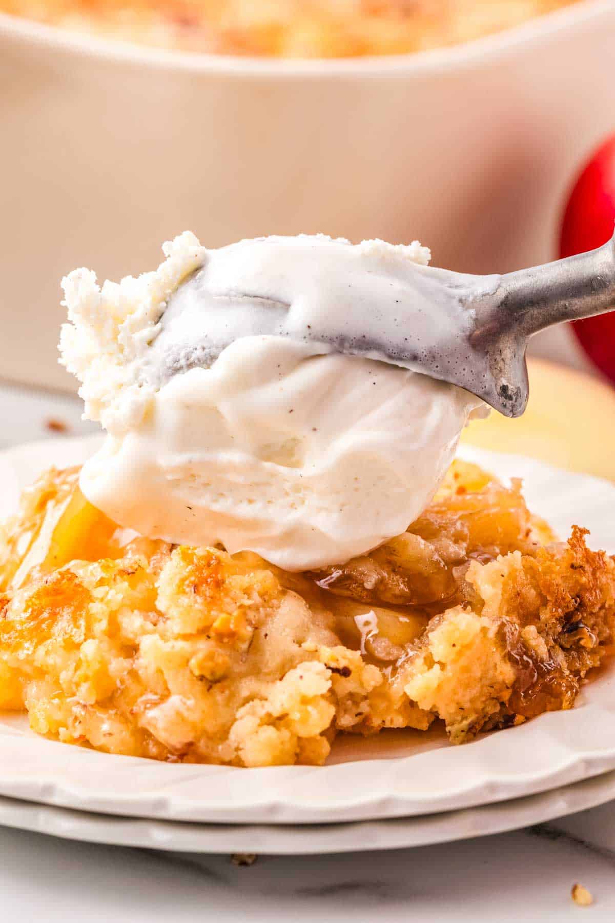 A scoop of ice cream is placed on the apple pie filling dump cake.