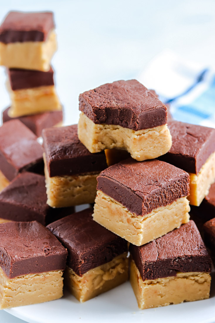 Pieces of Chocolate Peanut Butter Fudge stacked on top of each other and one piece has a bite taken out of it. 