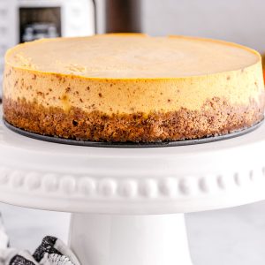 The finished Instant Pot Pumpkin Cheesecake on a white cake pedestal.