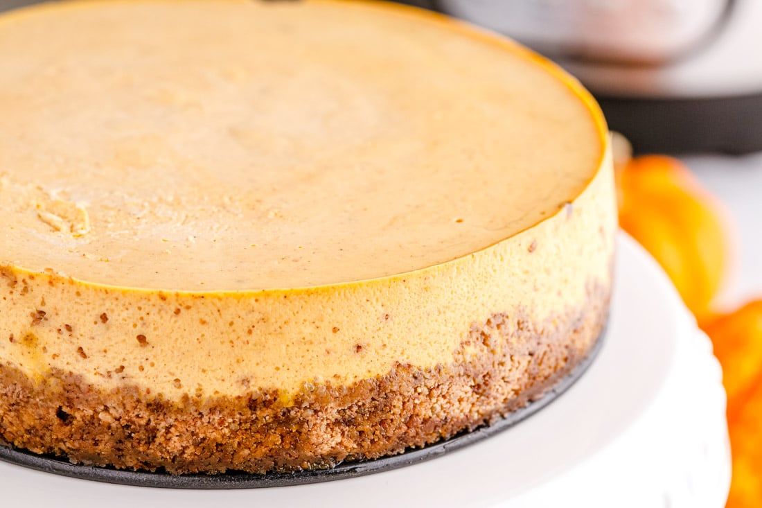 A close up picture of the finished Instant Pot Pumpkin Cheesecake on a cake stand.