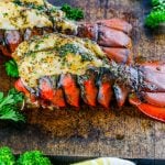 Two Smoked Lobster Tails on a wooden cutting board.