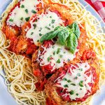 A close up picture of classic Chicken Parmesan on top of pasta with sauce.