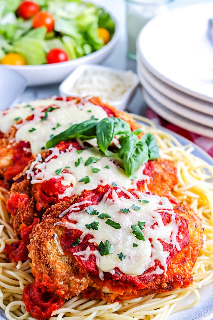 A close up picture of the finished Chicken Parmesan on a bed of spaghetti.