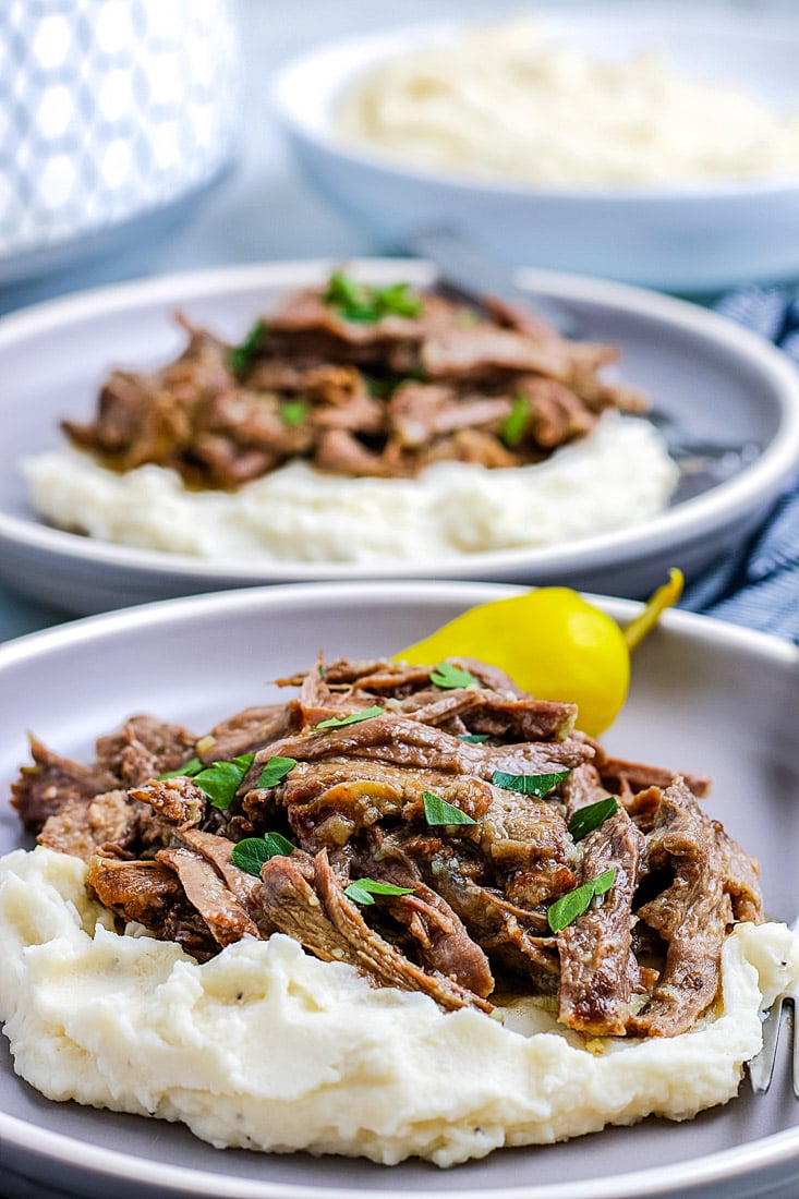 A close up picture of shredded Mississippi Pot Roast on mashed potatoes.