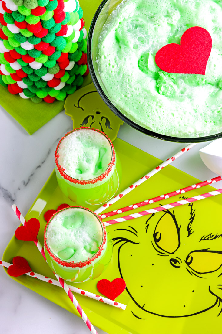 An overhead picture of the finished Grinch Punch in a punch bowl and two lear glasses.
