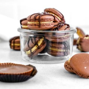 The finished Chocolate Peanut Butter Macarons stacked on each other in a glass jar.