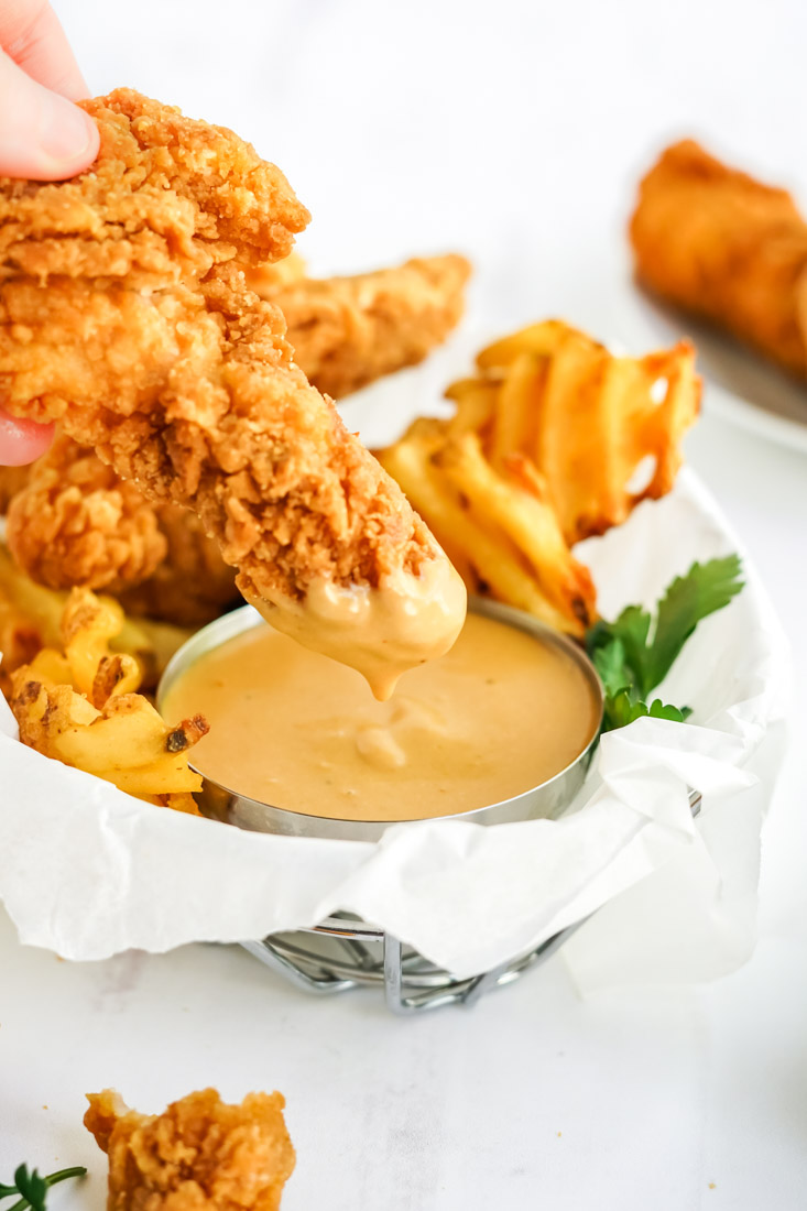 A chicken finger being dipped into homemade Chick Fil A Sauce recipe.