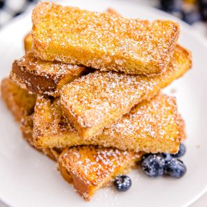A pile of Air Fryer French Toast Sticks on a white plate