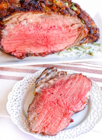 A slice of prime rib on a white plate.
