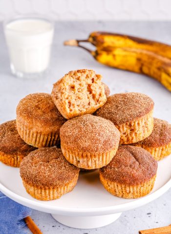 The finished Banana Cinnamon Muffins stacked on top of each other on a cake stand.