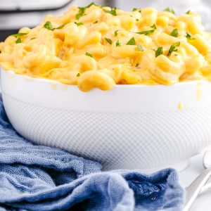 A close up picture of the finished Instant Pot Velveeta Mac and Cheese in a white serving bowl with chopped parsley on top.