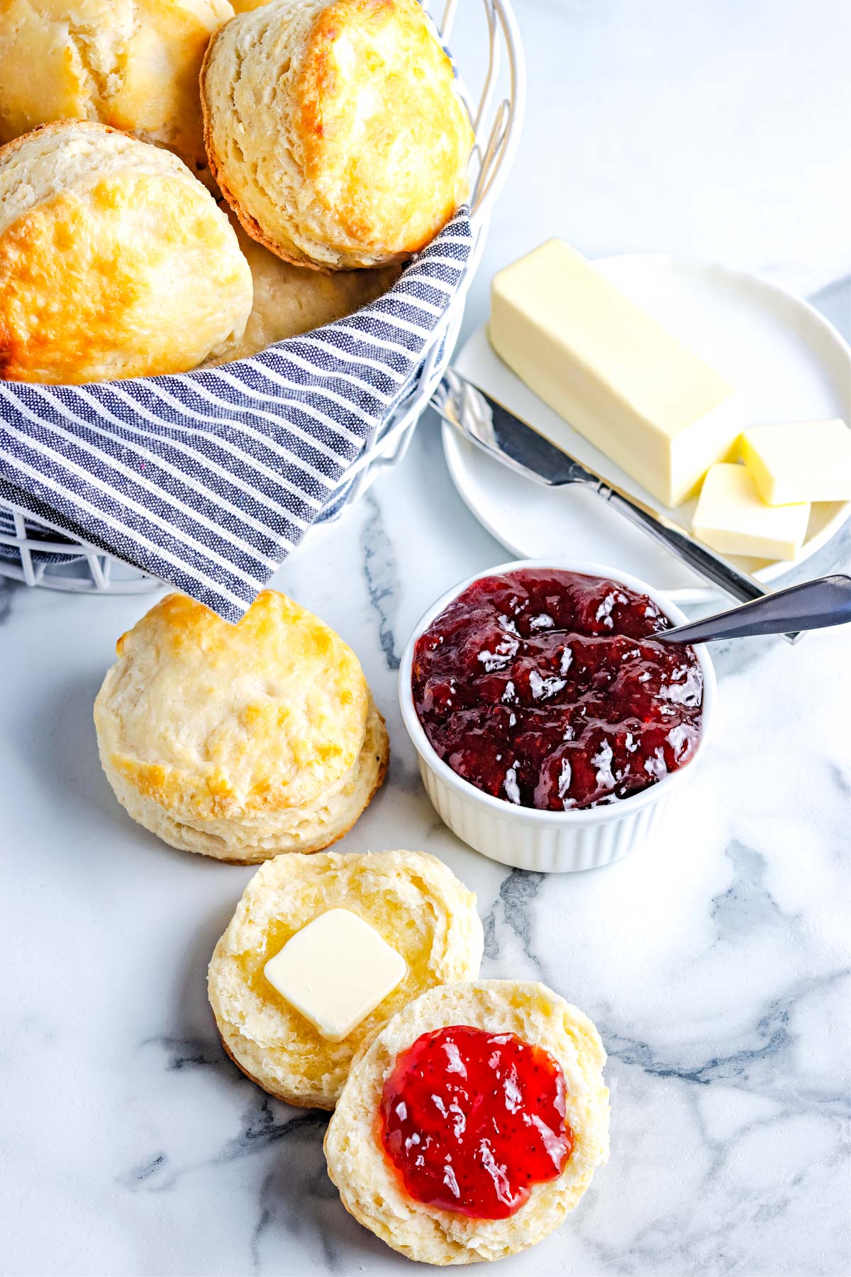 An overhead picture of buttermilk biscuit with jam and butter on them.