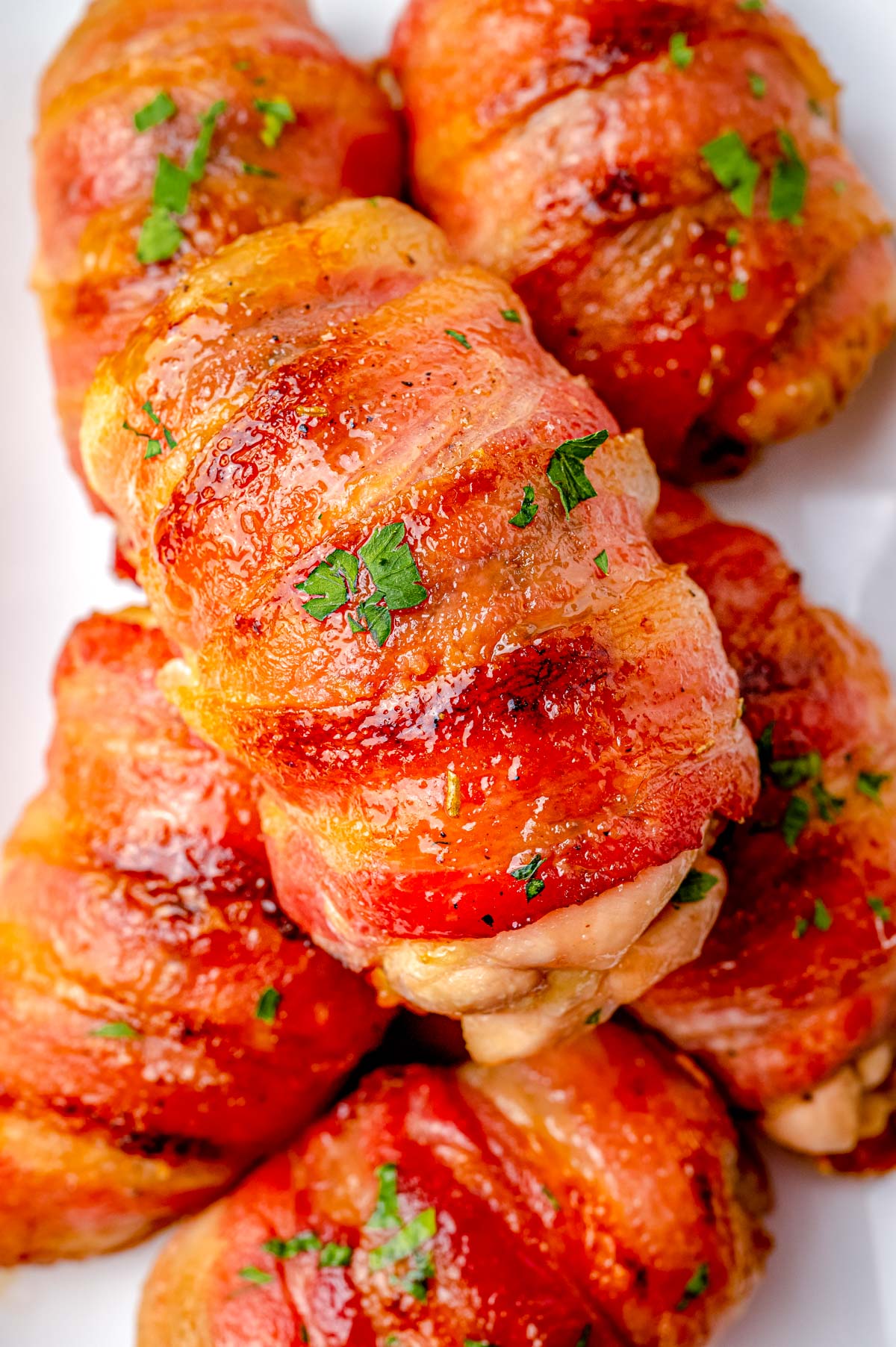 A close up picture of the finished Bacon Wrapped Chicken Thighs piled on a platter.