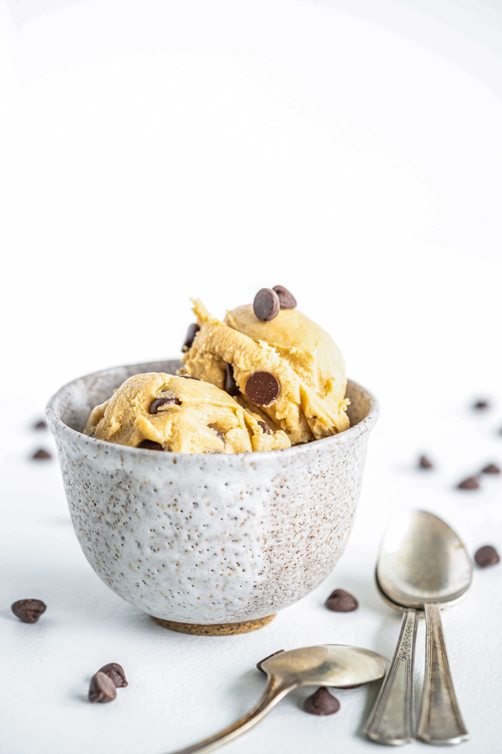 Cookie dough in a bowl with chocolate chips sprinkled all around.