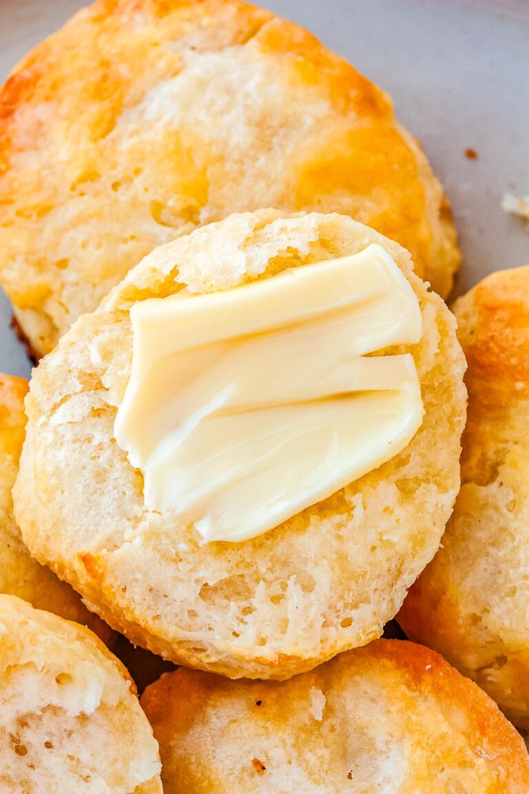 A biscuit cut in half and a pad of butter added to the top.