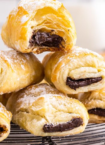 A stack of Puff Pastry Chocolate Croissants, one with a bite taken out of it.