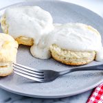 Split biscuits on a plate with white country gravy poured over them.