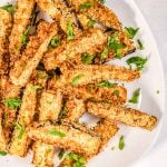 A close up picture of eggplant fries on a white plate.
