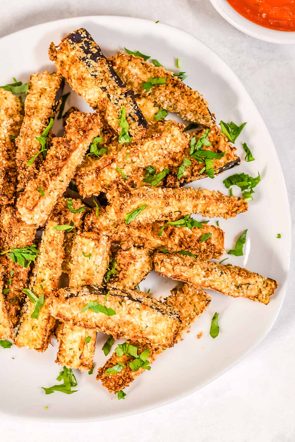A close up picture of eggplant fries on a white plate. 
