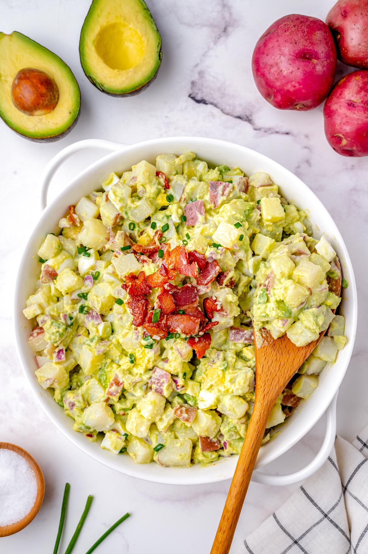 An overhead picture of the finished Avocado Potato Salad with a wooden spoon picking up some of the potato salad.