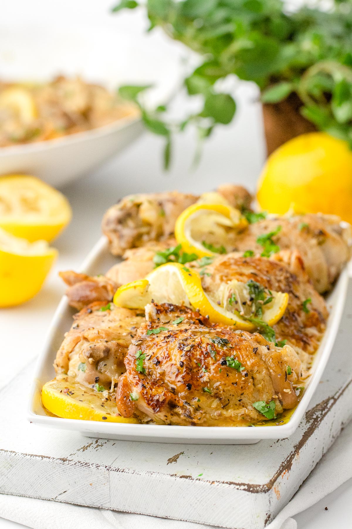 The finished nstant Pot Lemon Chicken Thighs on a white platter garnished with lemon wedges.