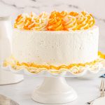 The finished Orange Creamsicle Cake on a white cake stand.