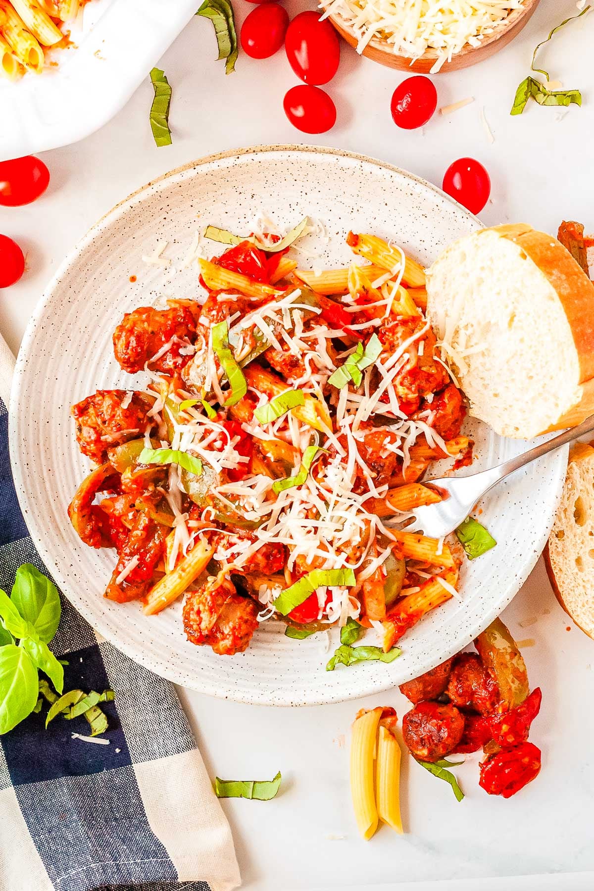 Some Pasta with Peppers, Onion, and Sausage in a white serving bowl and garnished with mozzarella.