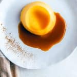An overhead picture of a Pumpkin Panna Cotta on a white plate garnished with caramel sauce and cinnamon.