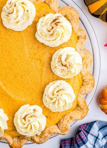 A close up overhead picture of the finished Pumpkin Chiffon Pie with dollops of whipped cream on it.